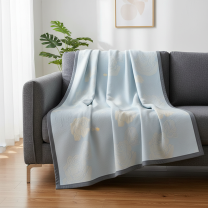 Blue Rose Bloom Cotton Blanket draped on a sofa in a modern living room